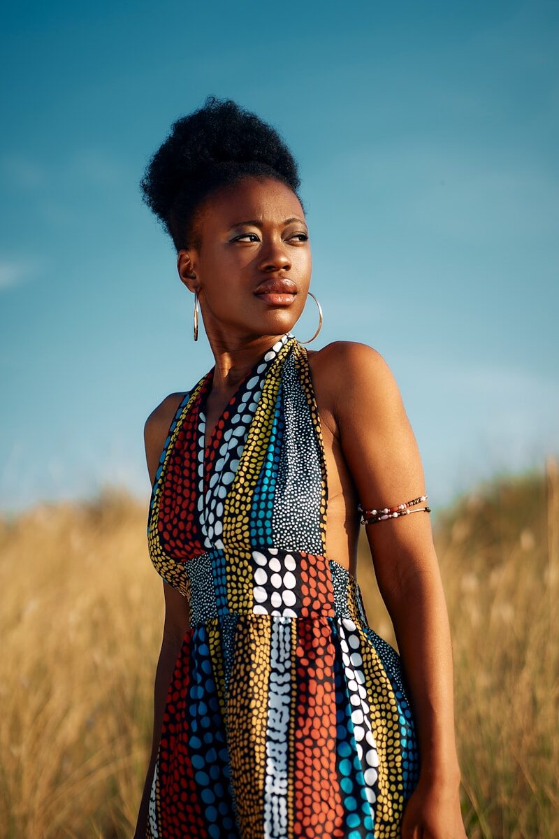 Young woman in vibrant patterned dress in golden field.